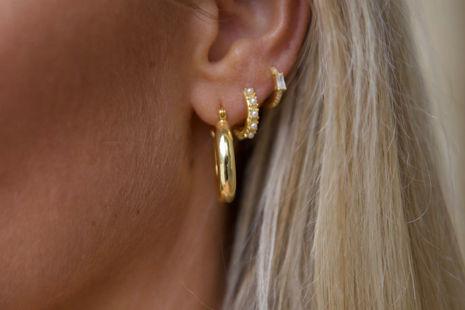 Woman looking away wearing beautiful gold hoop earrings in a stack - Liora Gold & Anna gold earring from LoveLocal Jewelry